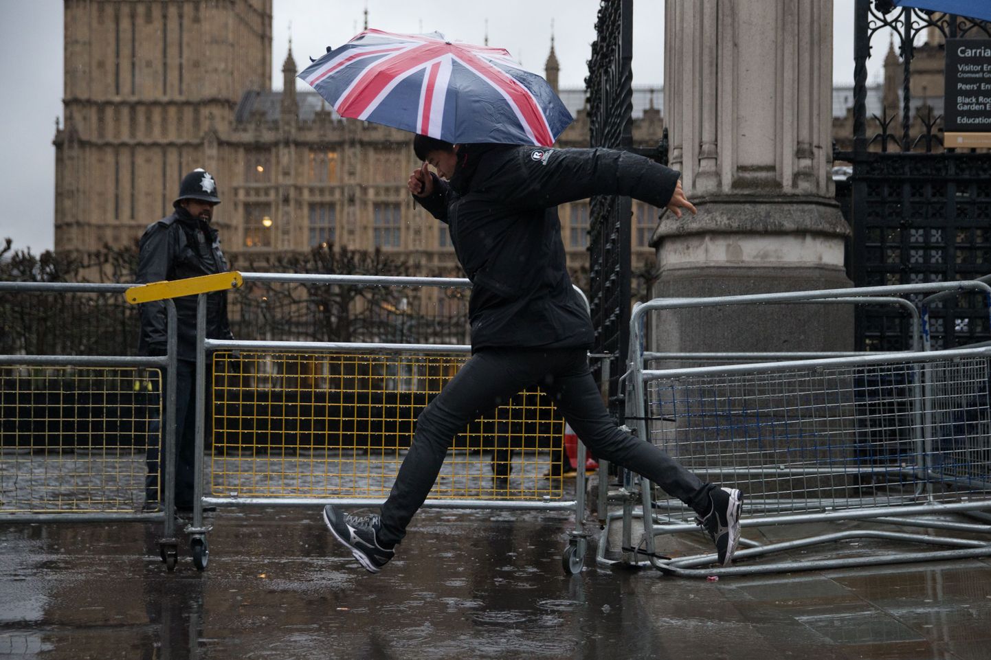 Jalakäija Londoni parlamendihoone juures üle lompide hüppamas.