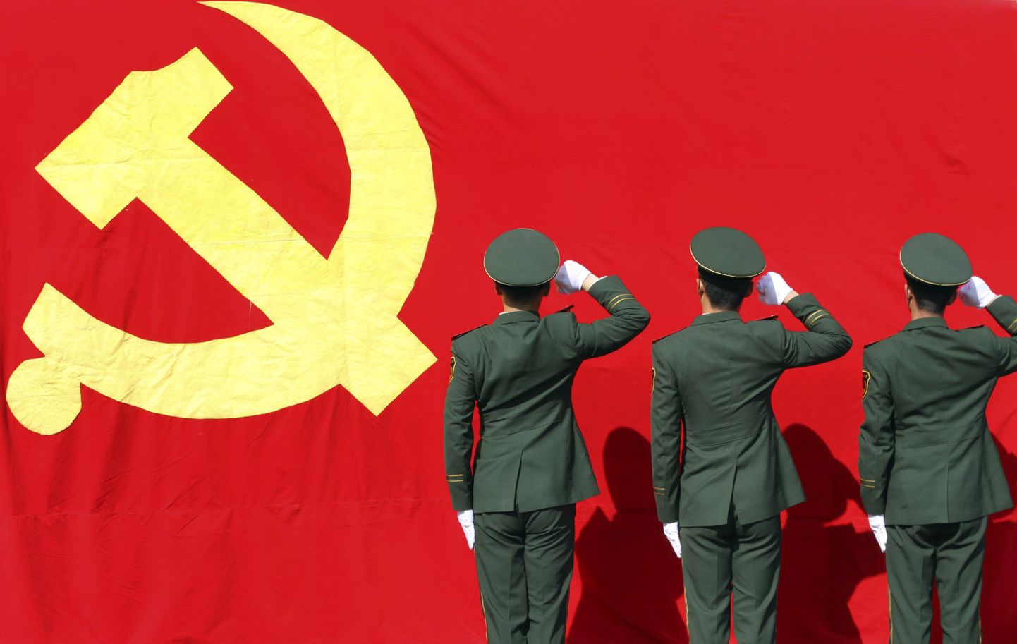 Hiina politseinikud kommunistliku partei lipu ees.