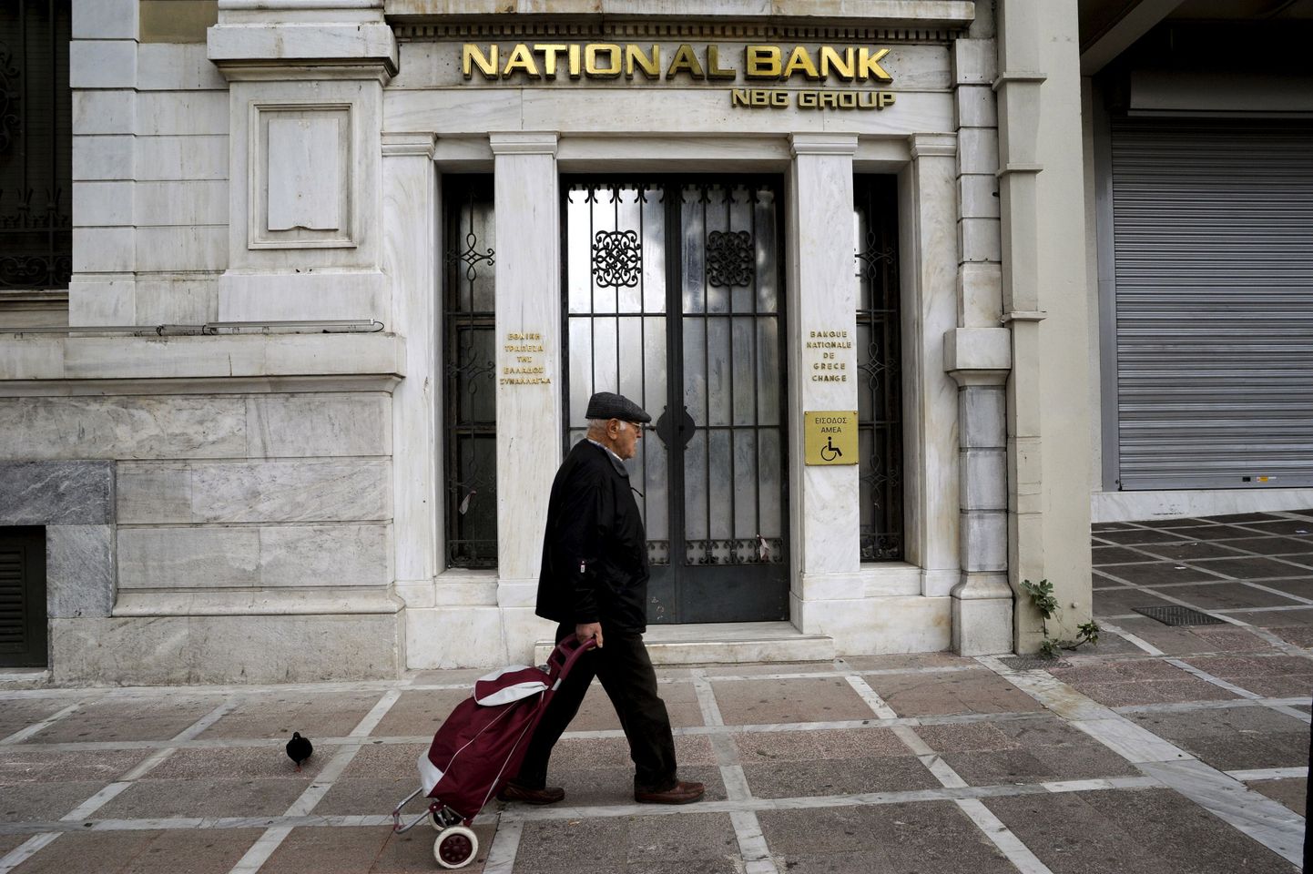 Kreeka majandust võib tänavu oodata kerge kasv. Pildil jalutav mees möödumas Kreeka pangakontorist Ateenas.
