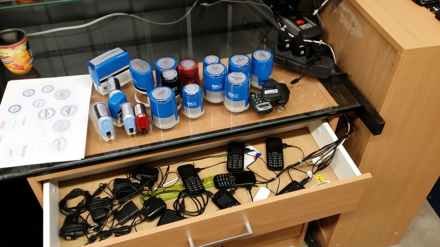 Печати и мобильные телефоны, найденные в ходе обыска в офисе подозреваемых.