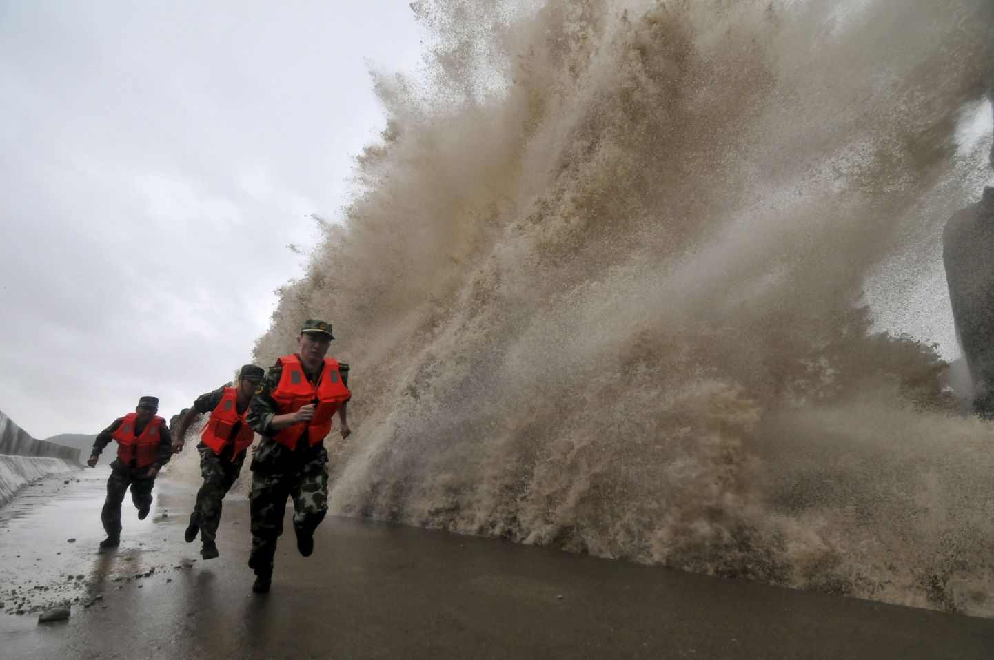 Hiina sõdurid täna Zhejiangi provintsis asuvas Wenlingis taifuun Fitow' tõttu tekkinud laine eest põgenemas.