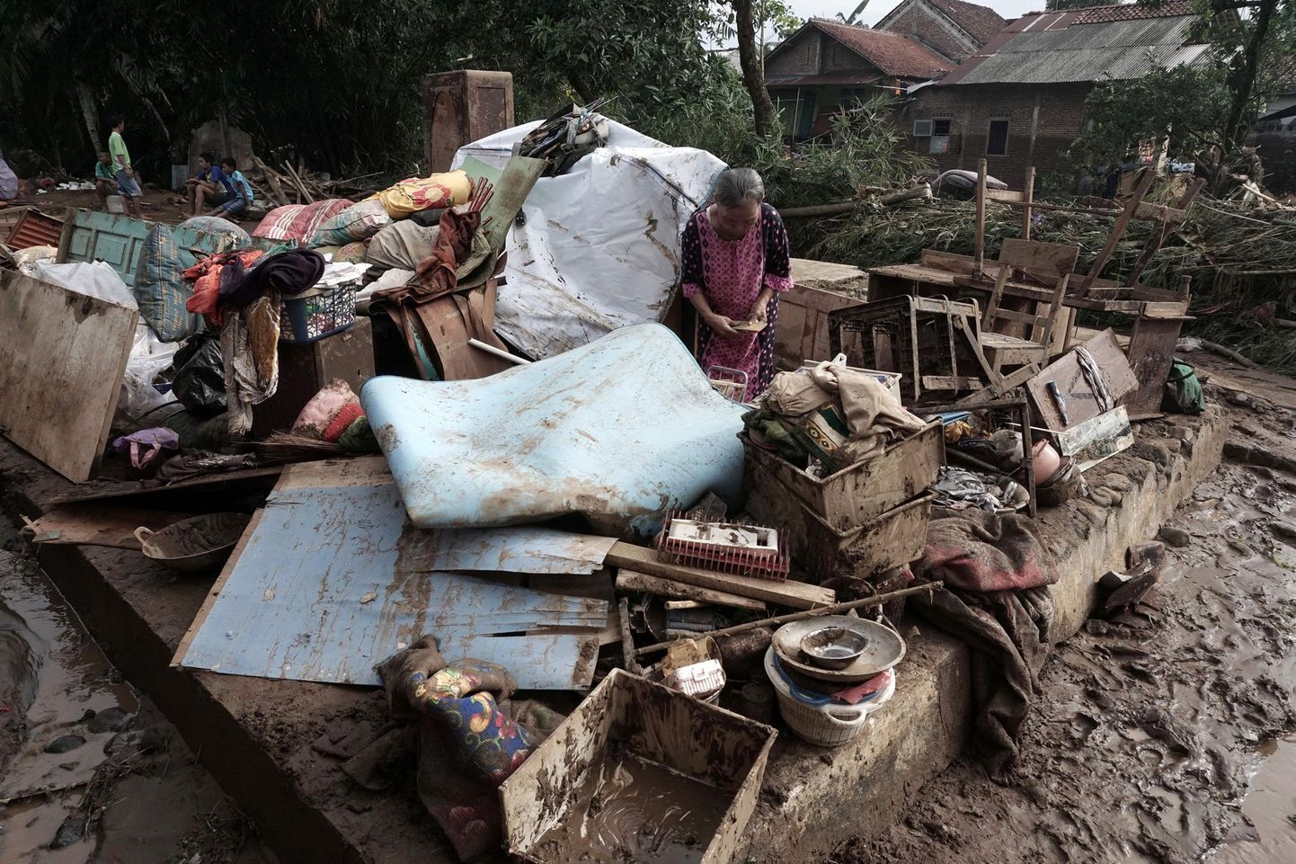 An Indonesian woman stands amid salvaged belongings after flash floods hit Kamulyan village in Banyumas, Central Java on June 19, 2016.  
Flash floods and landslides in central Indonesia have killed at least 35 people and destroyed dozens of homes, an official said June 19, as searchers scoured devastated villages for survivors. Dozens were also missing or injured following torrential rain and widespread flooding on the main island of Java, where thousands of homes have been swamped.
 / AFP PHOTO / ROHMAT SYARIF