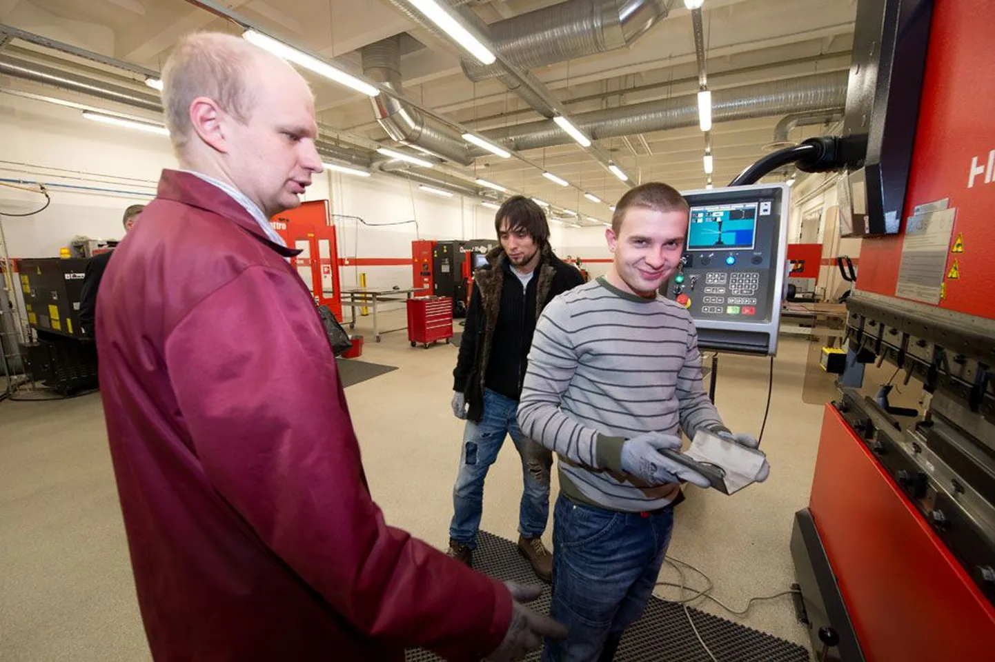 Õpetaja Aleksei Saareväli (vasakul) õpetab tööstushariduskeskuses töötuid noori metallitööpingil töötama. Pildil asetab Sergei Gritsan (24) lehtmetalli masina alla ja Alexey Ogay (25) vaatab pealt. Tegu on hästimakstud erialaga, kuhu pidevalt inimesi vajatakse.