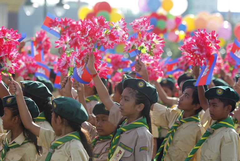 Students hold up plastic flowers and Cambodian flags during celebrations marking the 62nd anniversary of the country's independence from France in central Phnom Penh, Cambodia November 9, 2015. REUTERS/Samrang Pring