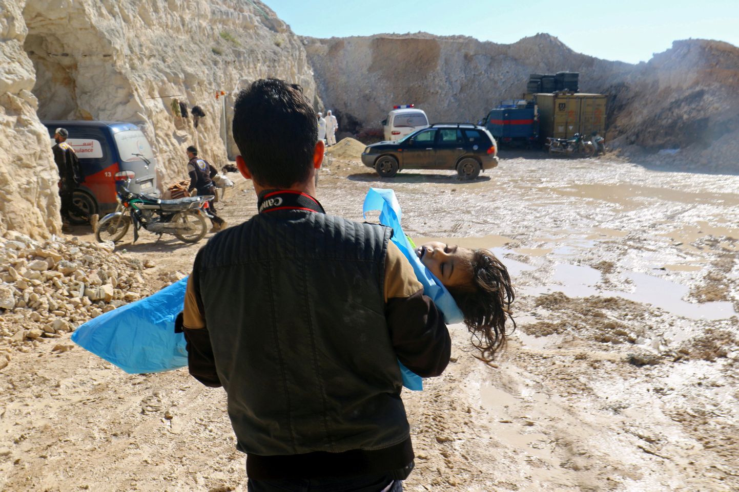 Мужчина несет ребенка после химической атаки в городе Хан-Шейхун.