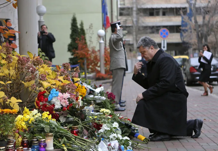 Ukraina president Petro Porošenko palvetamas Kiievi Prantsuse saatkonna ette pandud lillede ees.