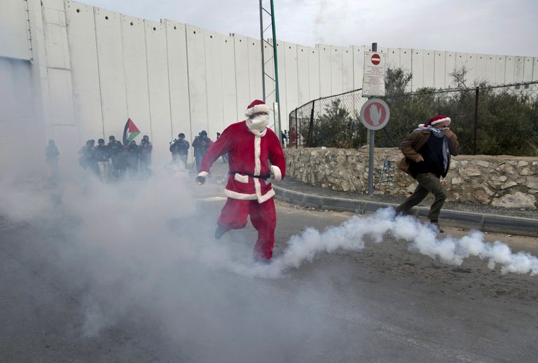 Jõuluvanaks riietatud palestiinlane müüri ääres pisargaasi eest jooksmas. Foto: Nasser Nasser/AP/Scanpix
