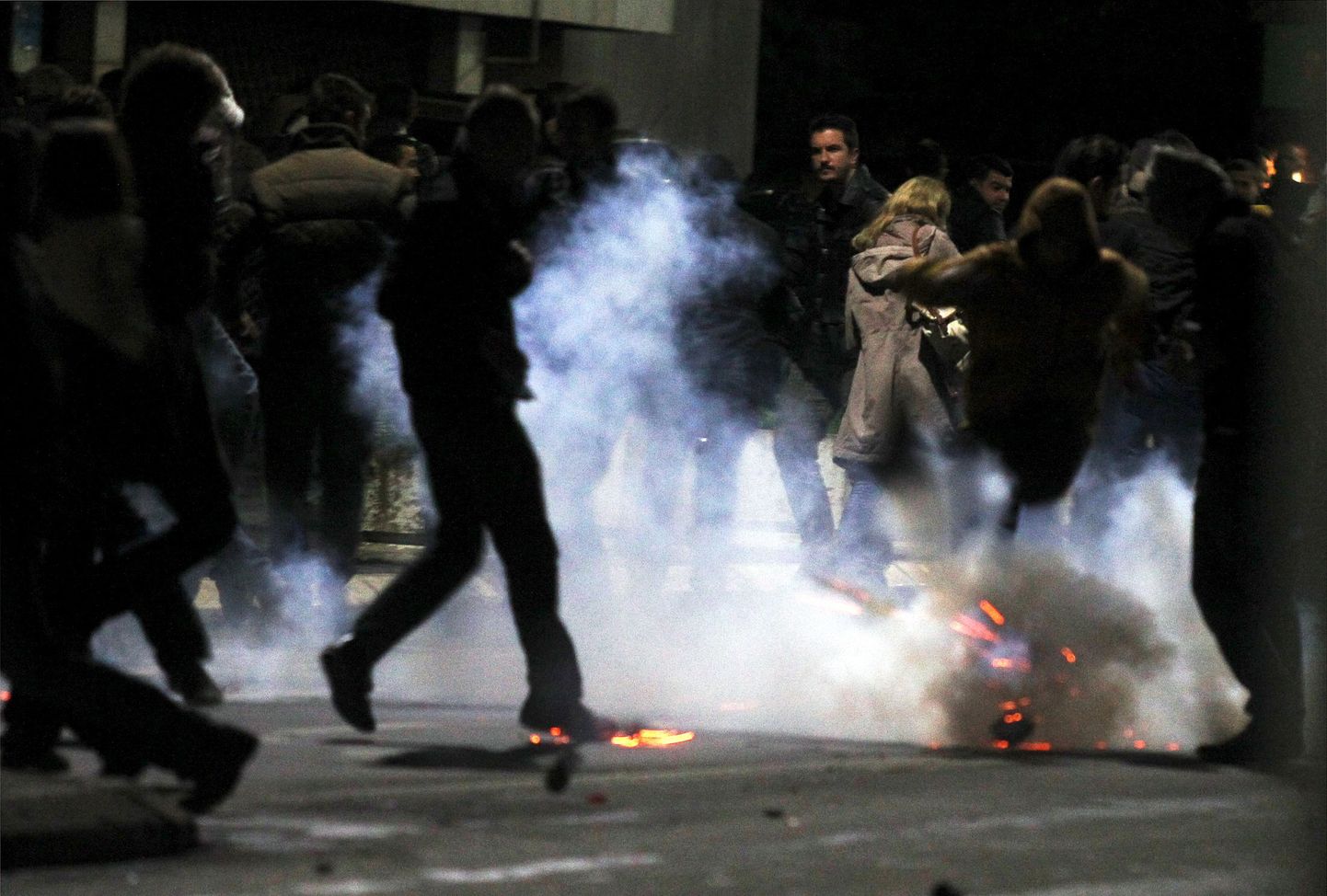 Люди бегут во время столкновений с полицией в Приштине 12 октября.