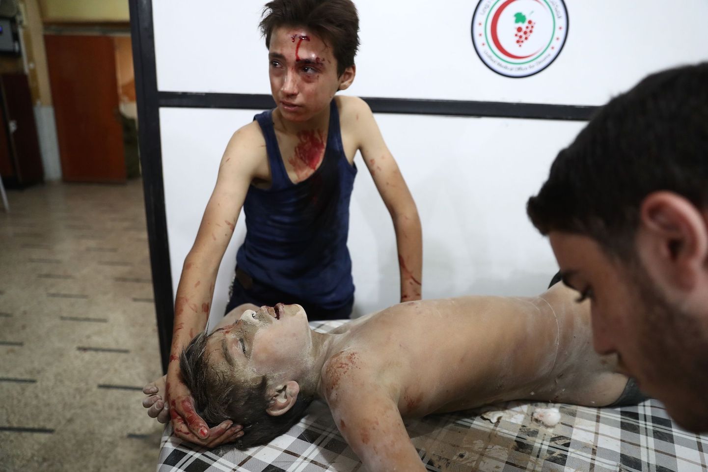 Mässuliste kontrolli all olevas Doumas valitsusvägede õhurünnakus viga saanud noor ohver teist vigastatut lohutamas.