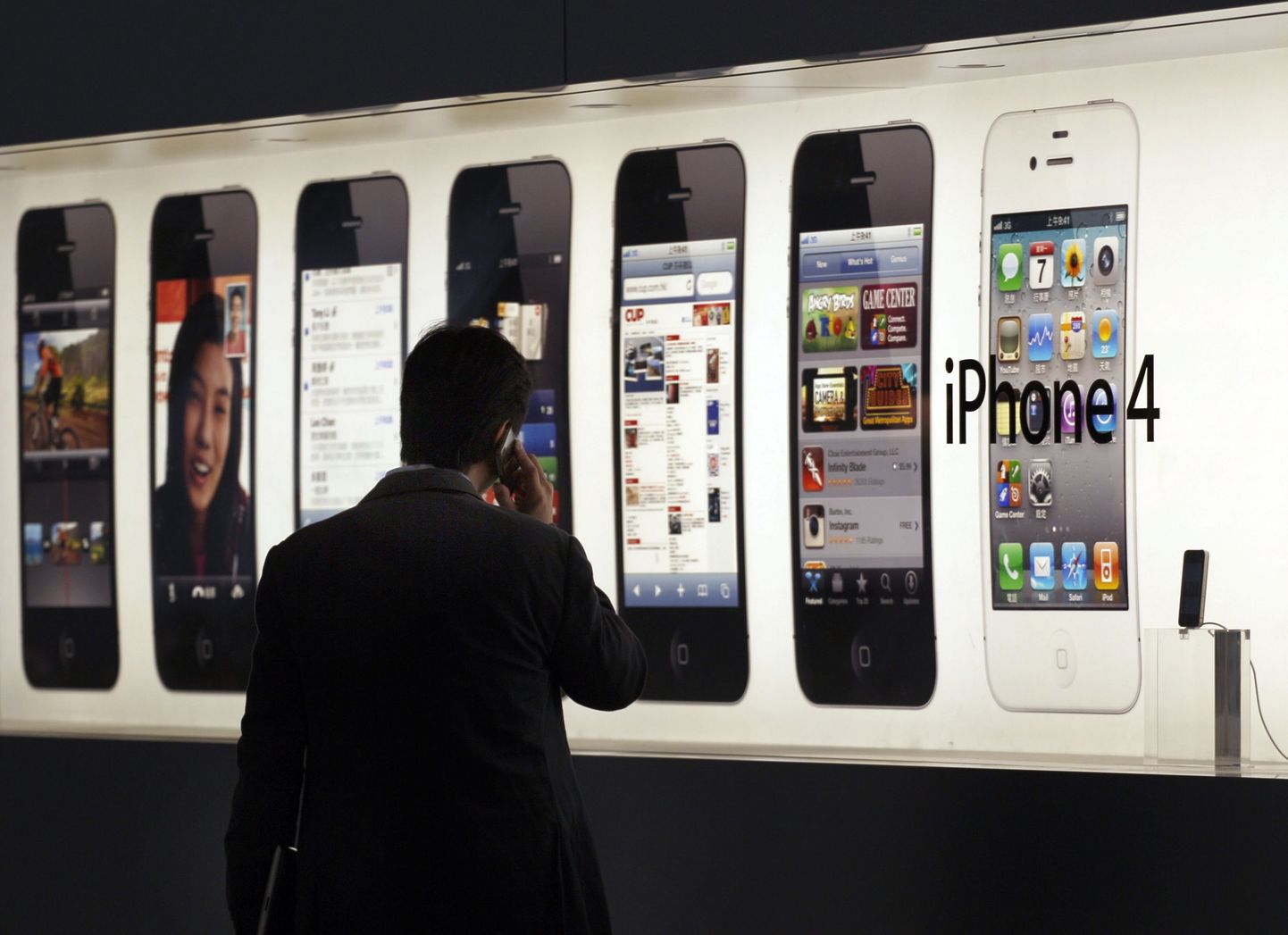 A man talks on an iPhone in front of an advertisement displayed at Hong Kong's first Apple Store at Two IFC before its opening in the financial Central district in this September 21, 2011 file photo. Apple Inc's quarterly results beat Wall Street estimates on stronger-than-expected demand for the iPhone, especially in the greater China region where sales jumped five-fold. Apple sold 35.1 million iPhones - which accounts for about half its revenue - in the March quarter of 2012, outpacing the 30 million or so expected by Wall Street analysts. REUTERS/Tyrone Siu/Files (CHiNA - Tags: BUSINESS)