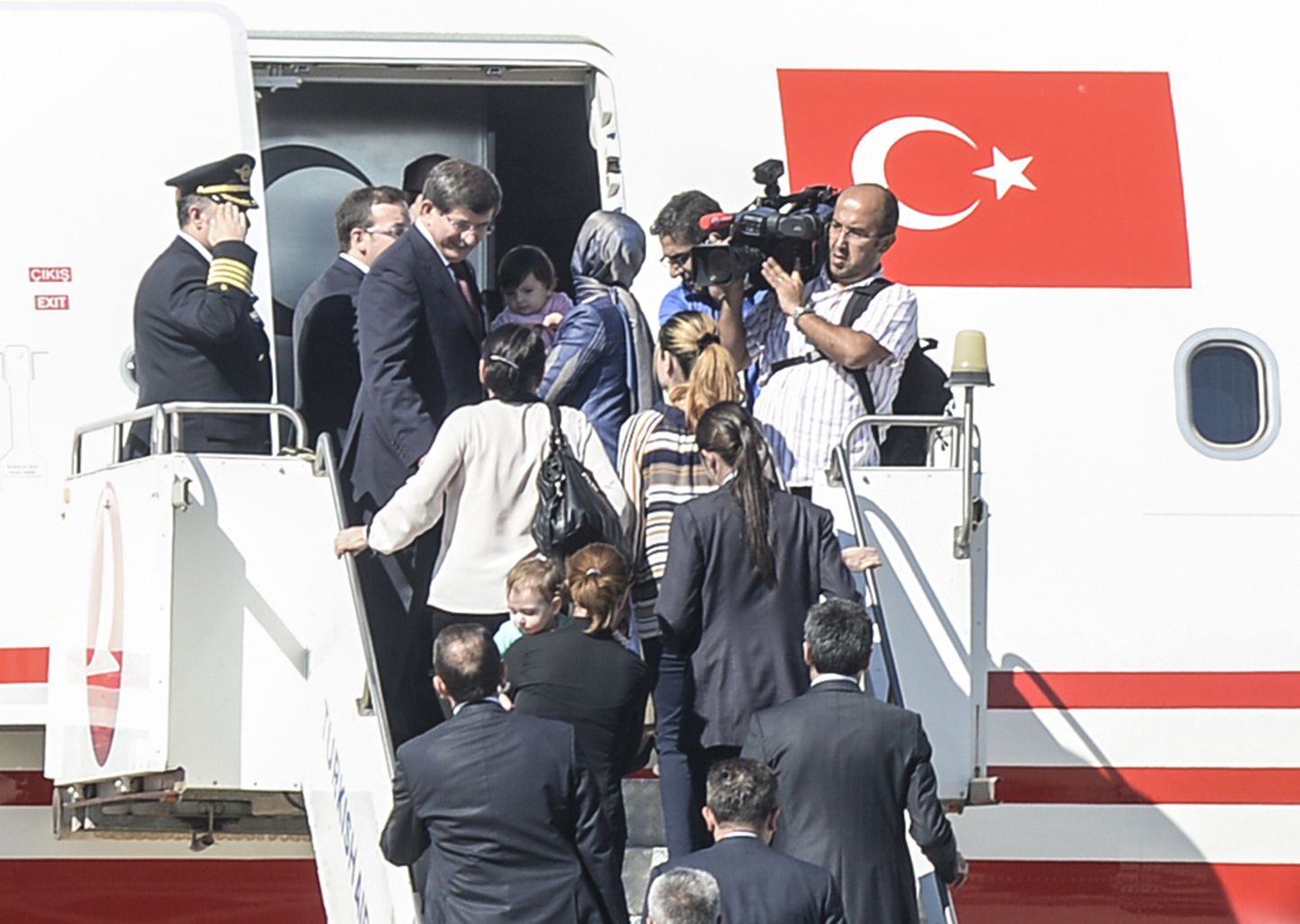 Türgi peaminister Ahmet Davutoğlu(vasakul)koos vabastatud pantvangidega täna Türgis Süüria piiri äärses Sanliurfa lennujaamas.