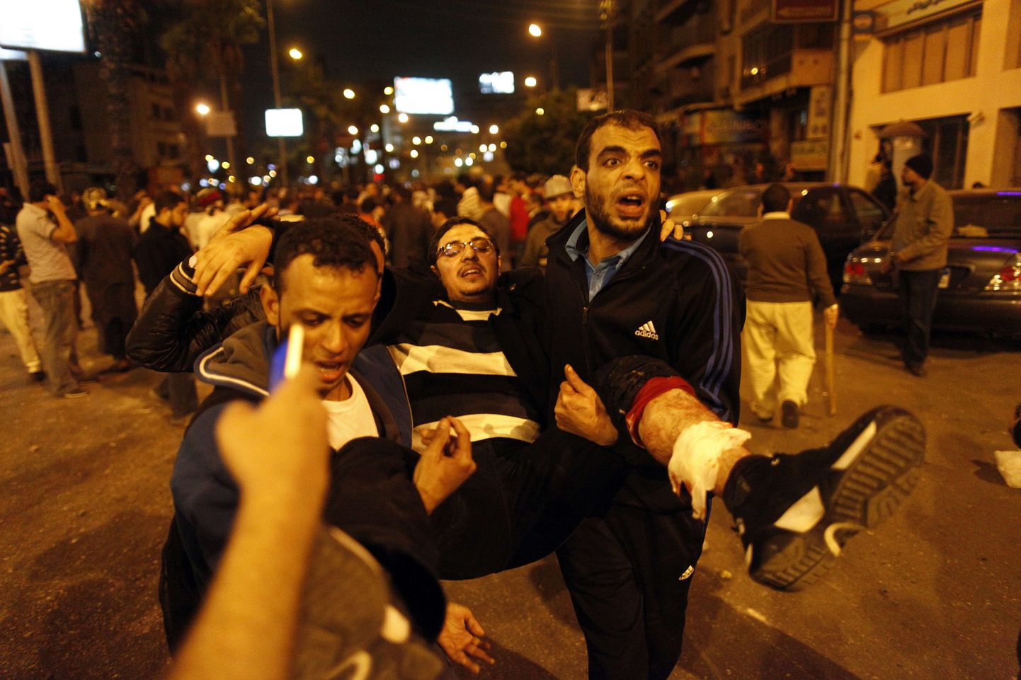 Members of the Muslim Brotherhood and supporters of Egyptian President Mohammed Morsi carry an injured comrade during clashes with anti-Morsi protestors on the road leading to the Egyptian presidential palace in Cairo on December 5, 2012. Supporters and opponents of Egypt's President Mohamed Morsi lobbed firebombs and rocks at each other as their standoff over his expanded powers and an Islamist-drafted constitution turned violent. AFP PHOTO/MAHMOUD KHALED