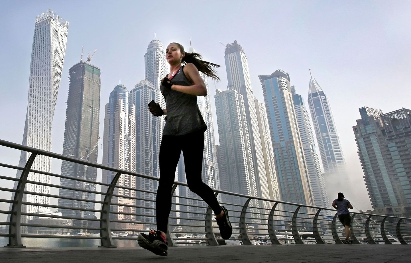Näitsik Dubai jooksmas Dubai pilvelõhkujate taustal.