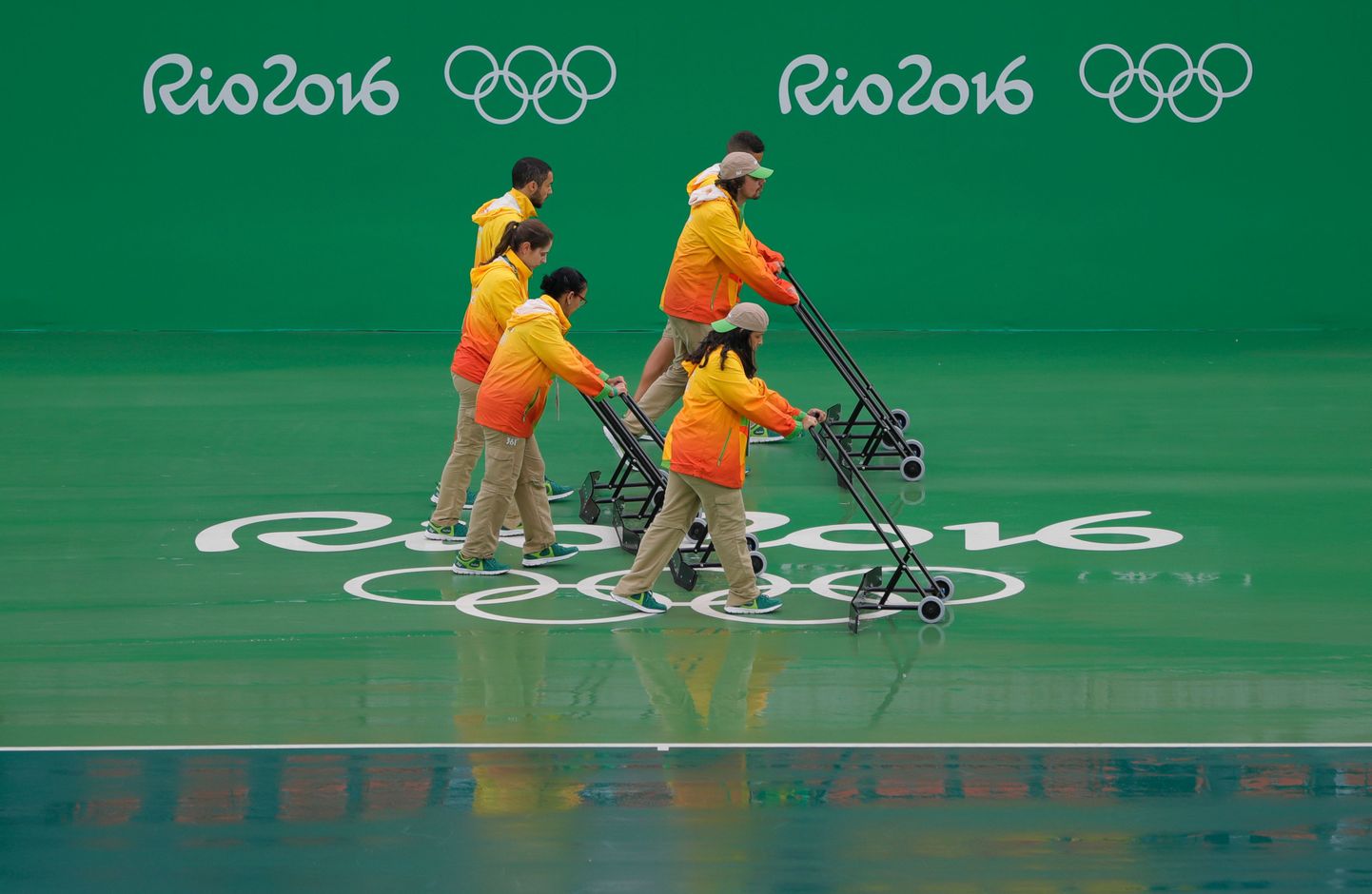 Vabatahtlikud püüavad Rios tenniseväljakuid kuivatada, et mängudega saaks lõpuks alustada.