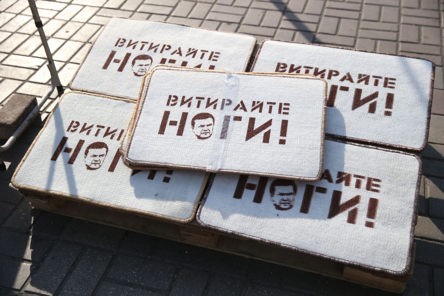 Kiievis müüdavad Viktor Janukovõtši näopildiga uksematid kutsuvad inimesi jalgu pühkima.