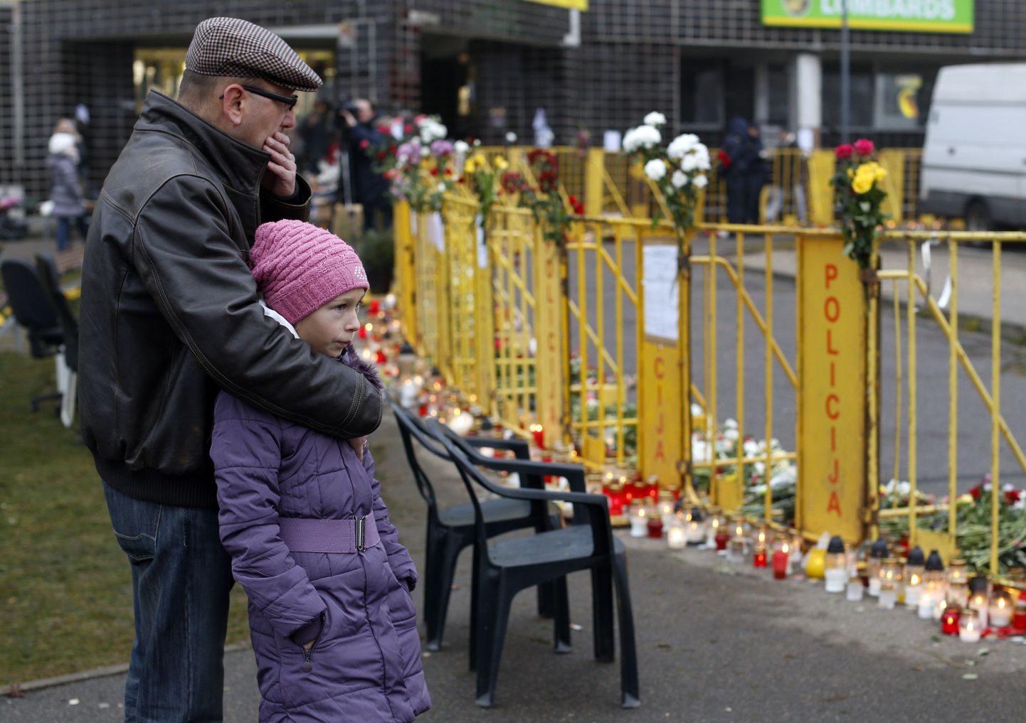 Inimesed seisavad Riia Maxima juures, kuhu on ohvrite mälestuseks toodud küünlaid ja lilli.