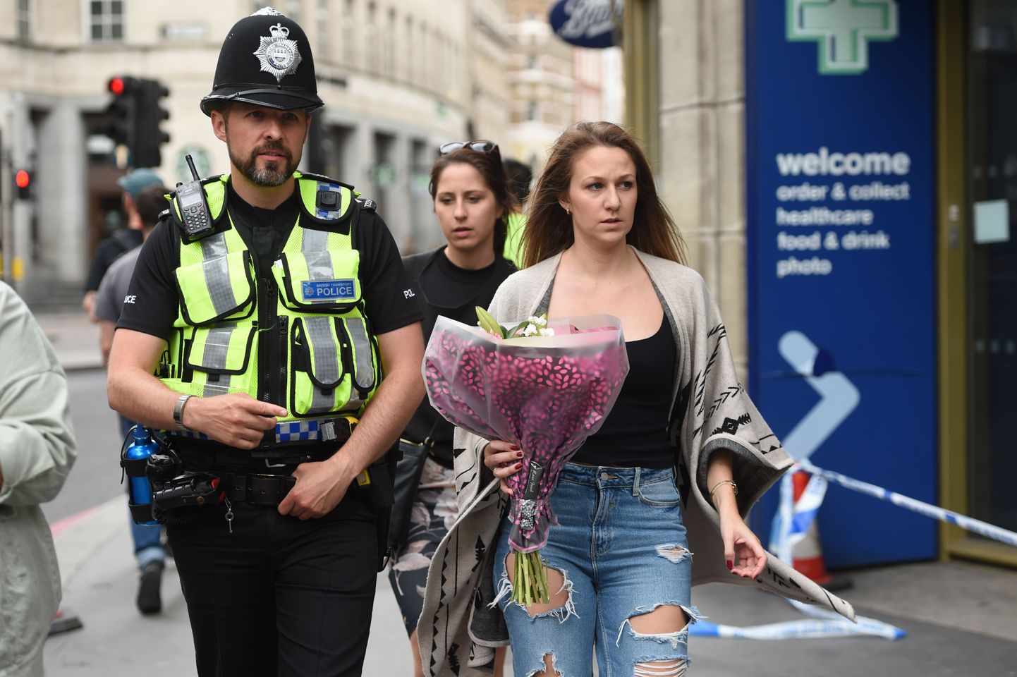 Korrakaitsja Londoni rünnakuohvrite mälestuseks lilli viiva naise kõrval.