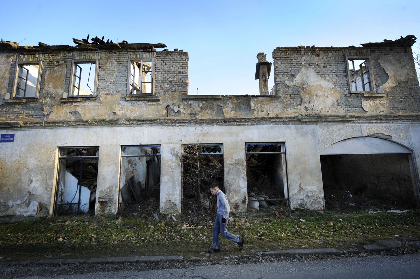 A boy walks past a building destroyed in the 1991-1995 Serbo-Croatian war, on January 18, 2011 in the central Croatian town of Dvor.