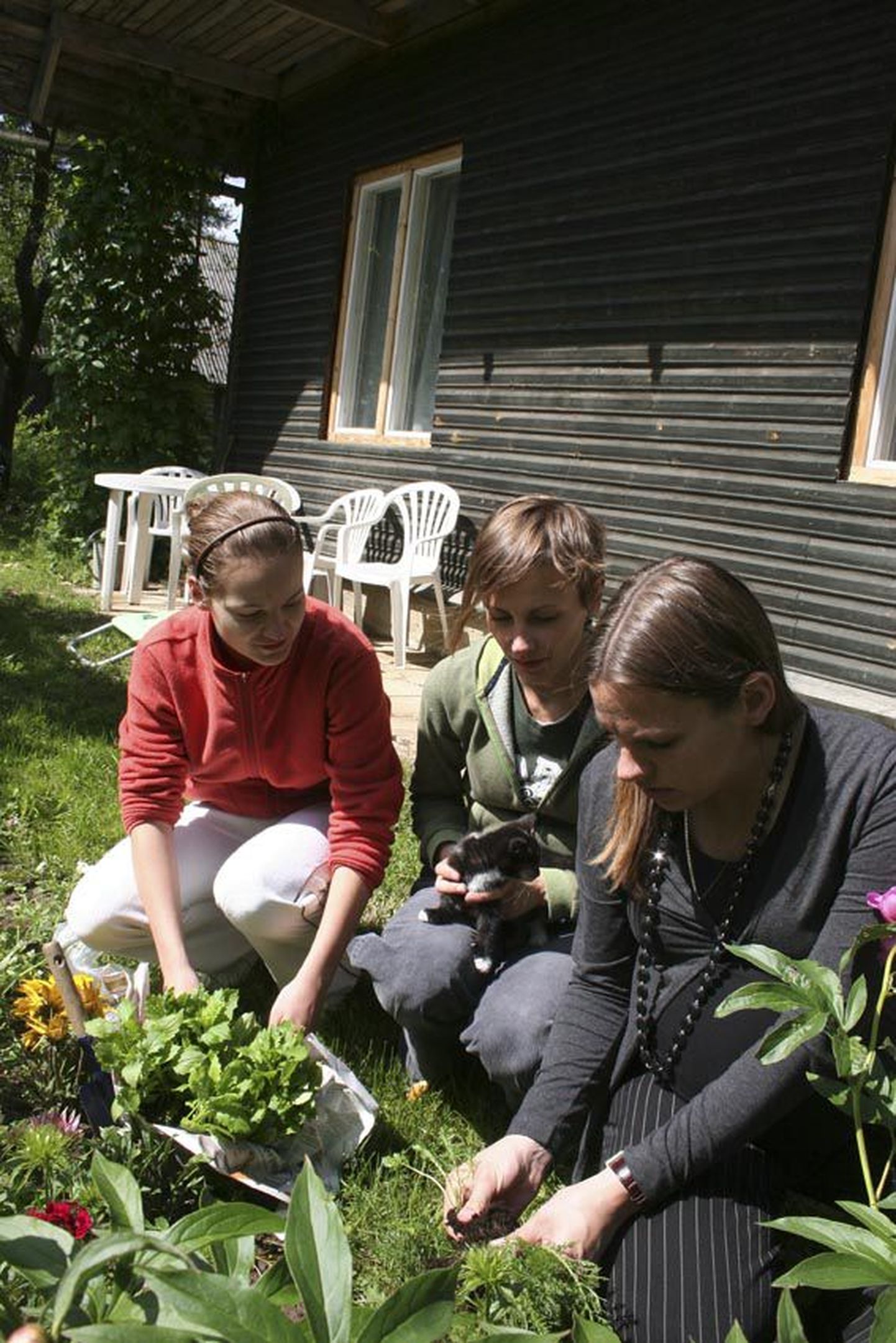 Merike Kuhhi tütred Elts, Triinu ja Liisa oma ema koduaias askeldamas.