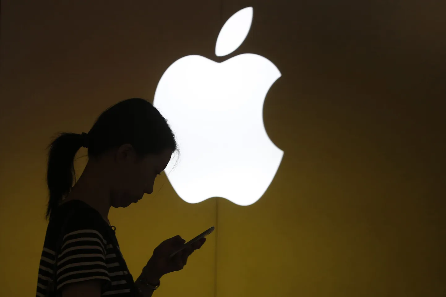 Naine vaatab oma mobiiltelefoni Apple'i logo ees Šhangais.
