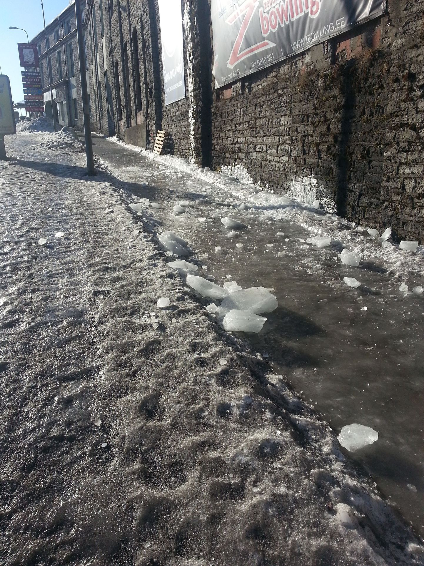 Kiilasjääs kõnniteele on katuselt kukkunud suured jäätükid.