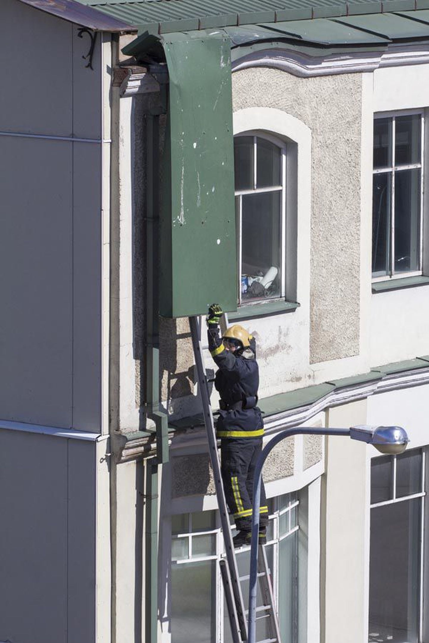Päästjad tõid Tartu tänav 9 hoone katuse servast alla rippuva pleki ohutult maapinnale.