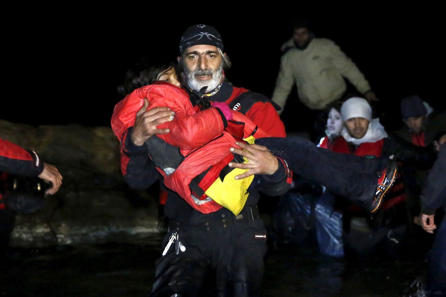 Греческий волонтер с ребенком беженцев.