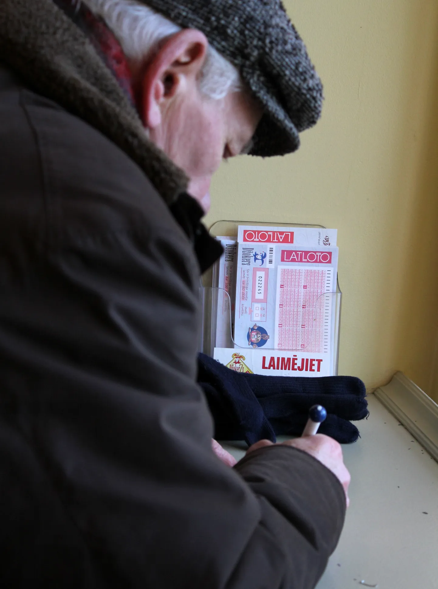 Vīrietis aizpilda "Latvijas Loto" kuponu.