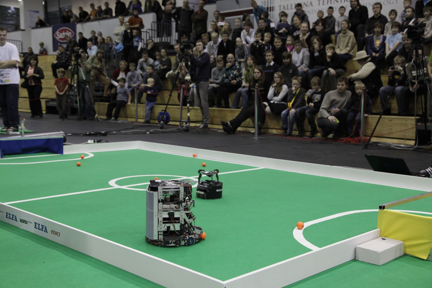 О том, что интерес к выставке Robotex, организуемой Таллиннским техническим университетом, растет год от года, свидетельствуют рекорды посещаемости: в 2012 году ее посетили 6,5 тысячи человек, более 500 участников и померились силами около 150 роботов. На фото: главное соревнование выставки – футбол, робот Palmer против малыша  Drag-On.
