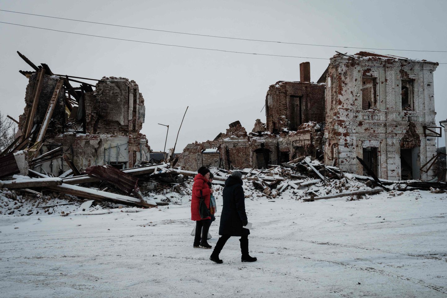 Kohalikud elanikud Kupjanskis 13. veebruaril kõndimas mööda hävinenud hoonest.