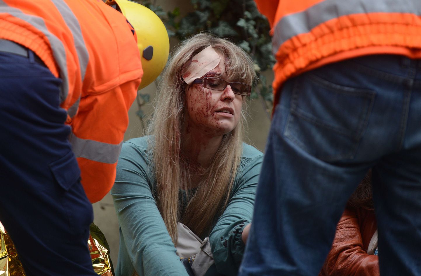Päästetöötajad abistamas plahvatuses viga saanud naist.