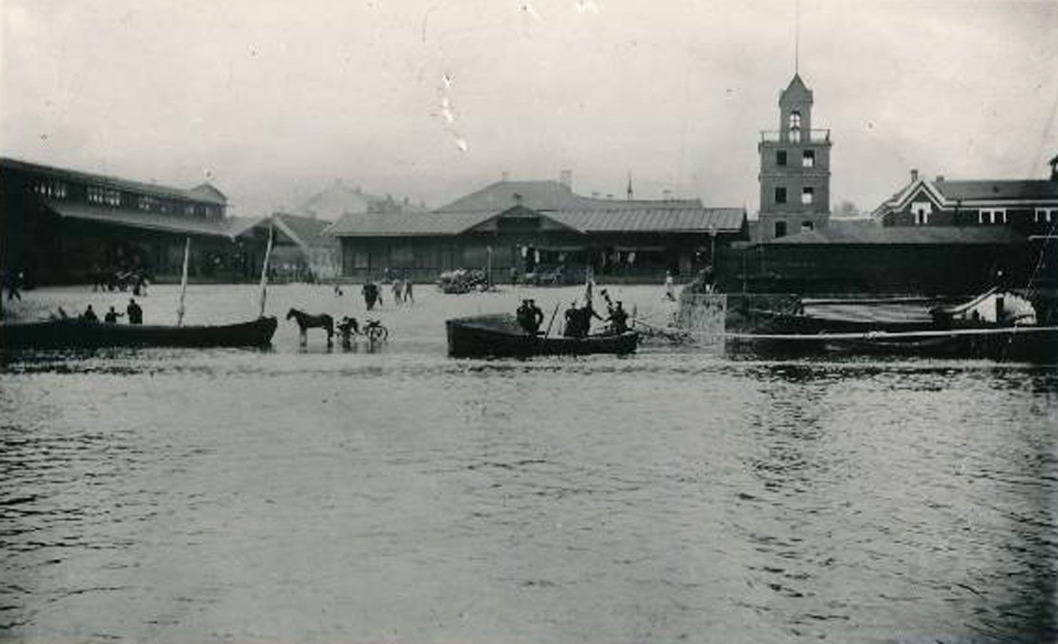 Fotole on jäädvustatud 1899. aasta üleujutuse aegne söögiturg. Vasakul paistaks praegu Tartu sammastega kaubamaja, parempoolses osas on vana pritsumaja torn, mille asemel on nüüdsel ajal park.