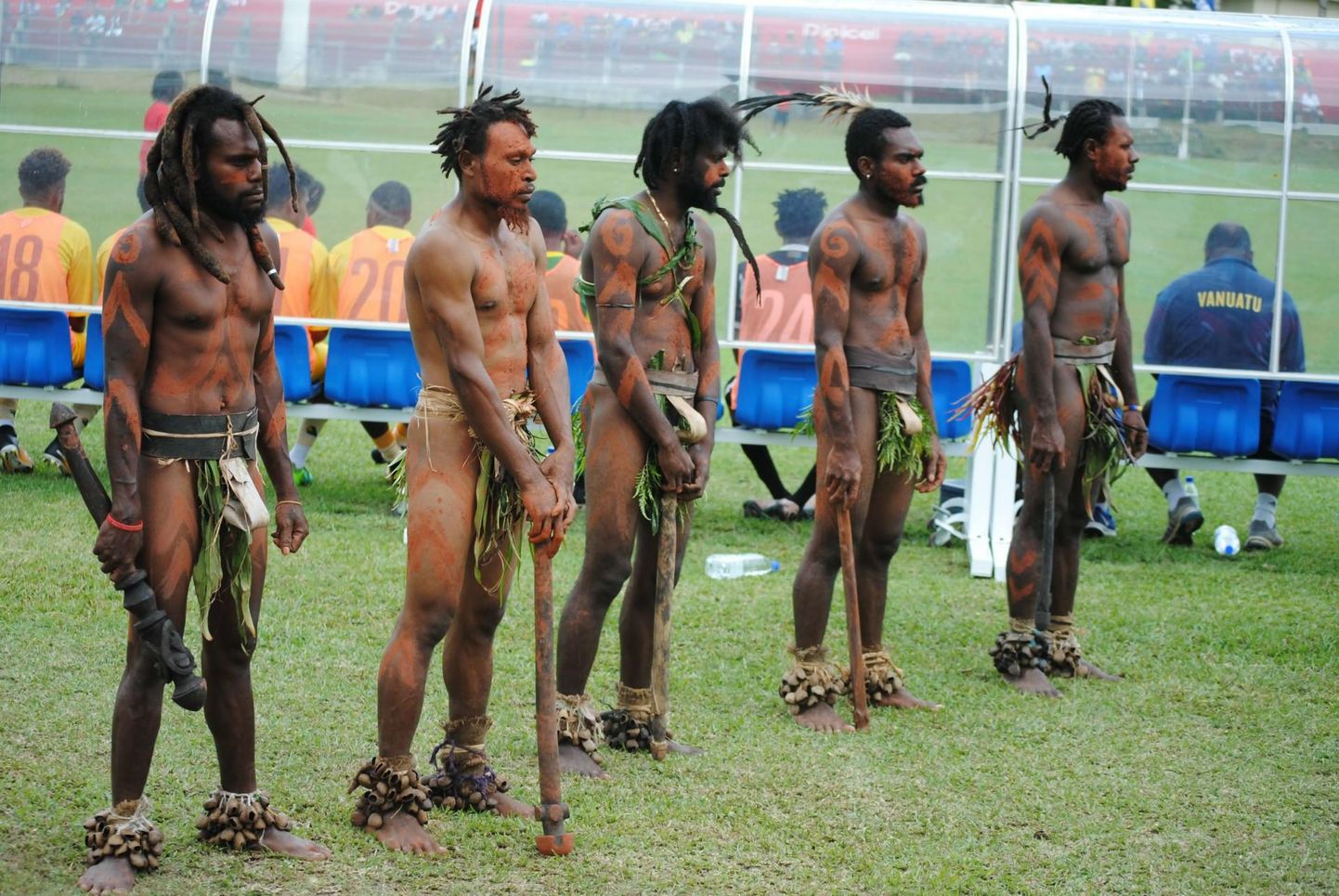 Vanuatu ja Eesti koondise maavõistlus jalgpallis. Vanuatu koondise vahetuspingi taga seisavad auvalves rahvarõivais kohalikud.