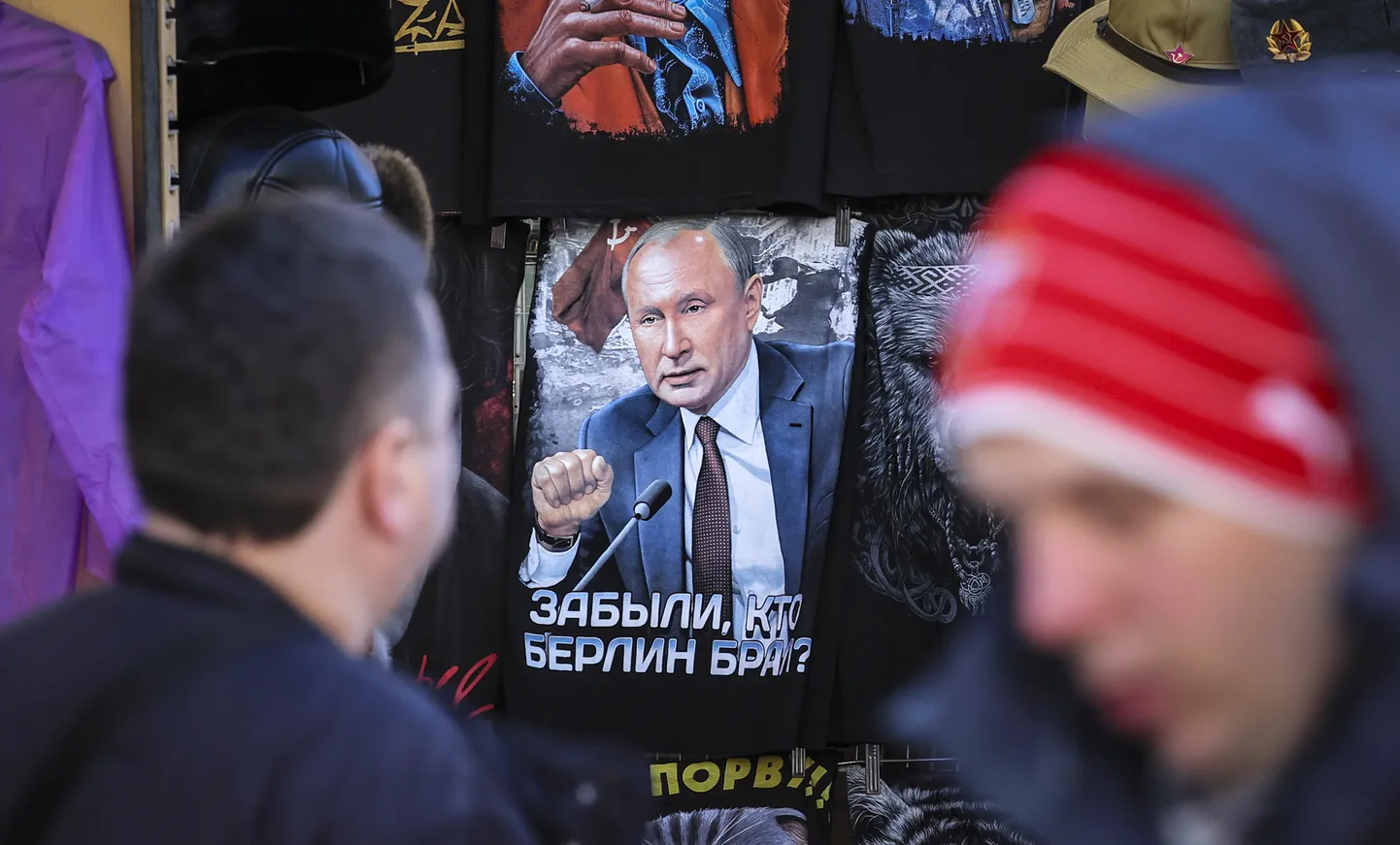 Cilvēki Maskavā pie veikala, kura skatlogā redzams T-krekls ar diktatora Putina attēlu