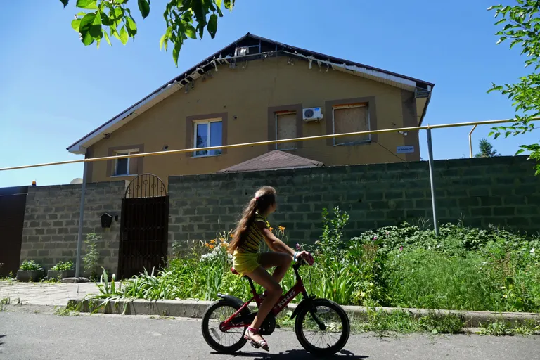 Tänane pilt Donetskist: laps sõidab mööda mürsurünnaku käigus kahjustada saanud majast. Foto: Igor Maslov/Sputnik/Scanpix