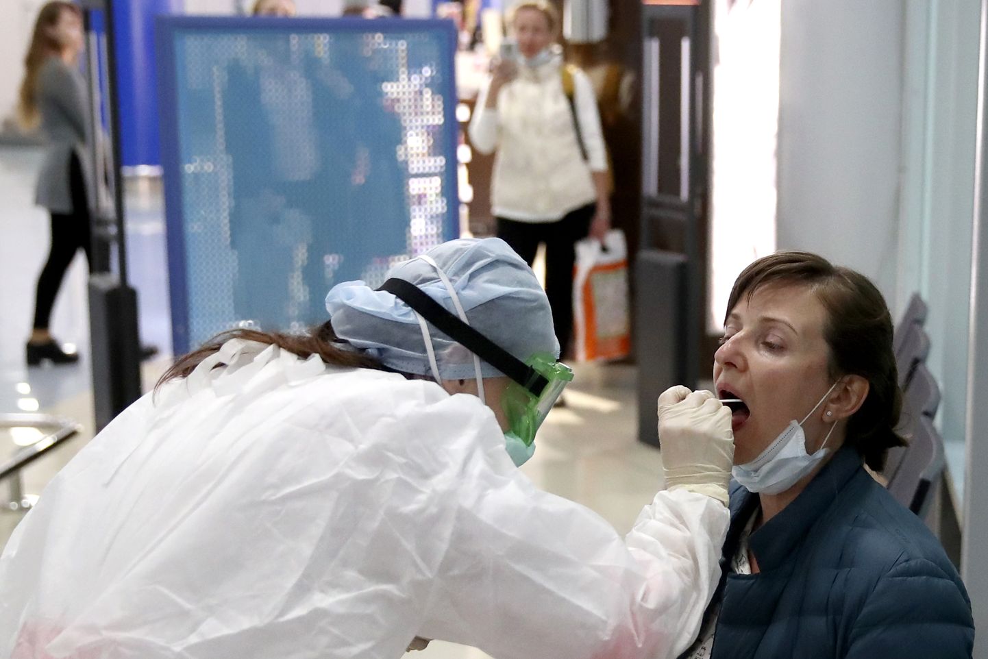 Медик берет пробу у пассажира в Минском аэропорту.
