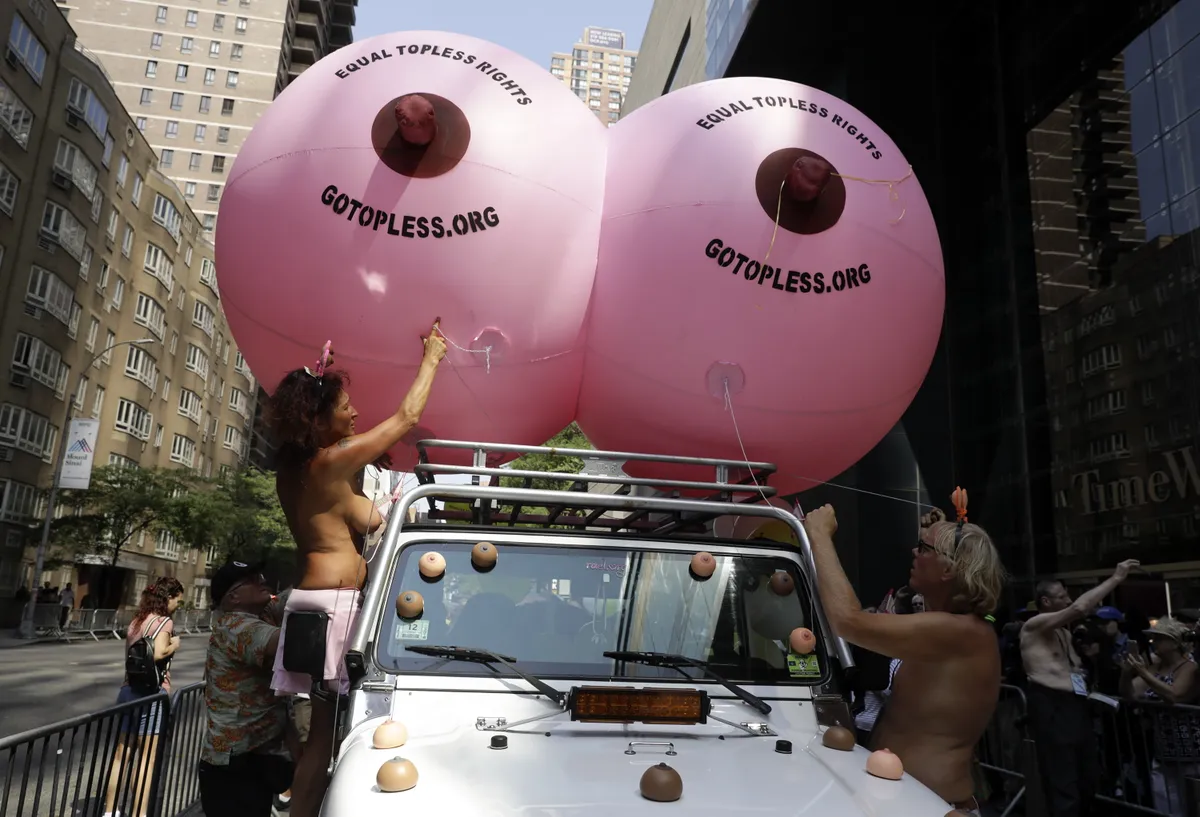 2018. gada 26. augusts, Ņujorka, ASV. Puskaili cilvēki piedalās toplesa parādē, kas aicina aizdomāties par sieviešu līdztiesību. Topless jeb augšdaļas atkailināšana akcentē
jautājumu: kāpēc vīrieši var, bet sievietes nedrīkst sauļoties pludmalē kailu augšdaļu.