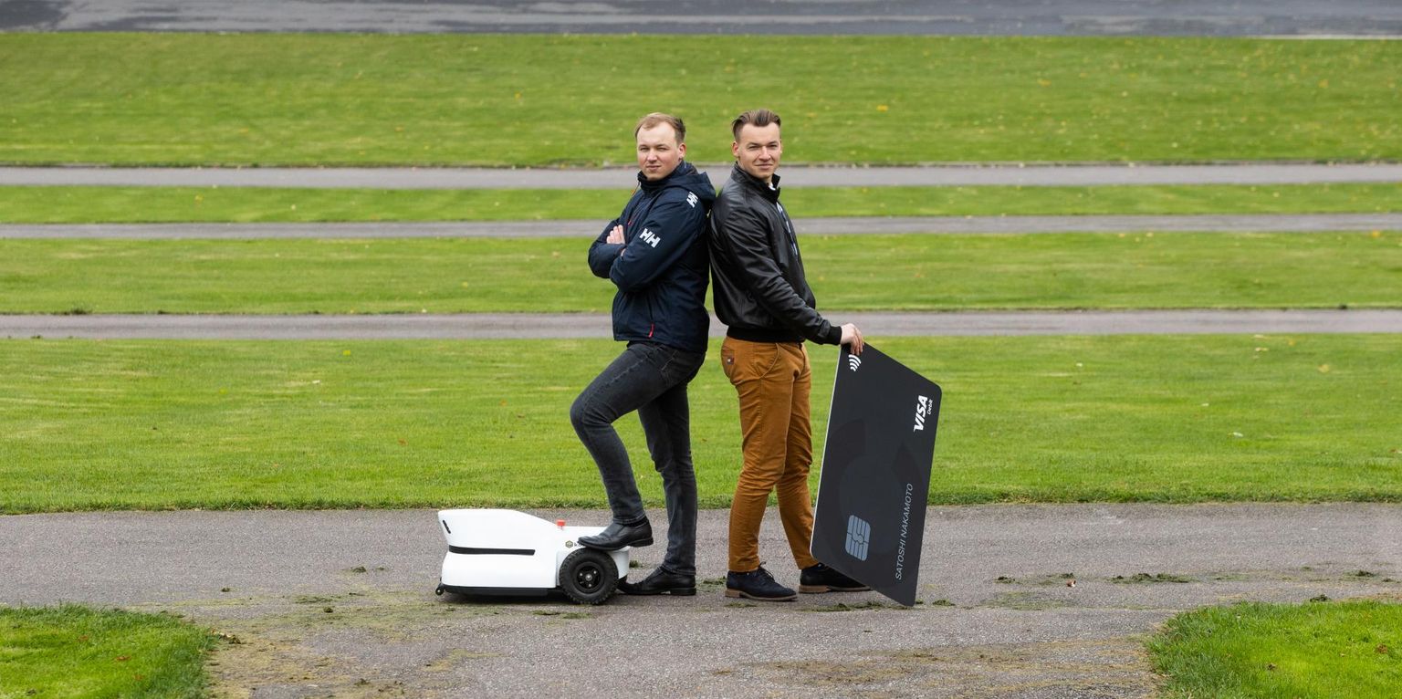 Vennad Joan (vasakul) ja Kristjan Kangro Tallinna lauluväljakul, kus Joani ettevõtte loodud intelligentne robotmuruniiduk hoiab iseseisvalt korras suurt muruplatsi. Kristjan toetab käega kümneid kordi suurendatud investorkaardi näidist.