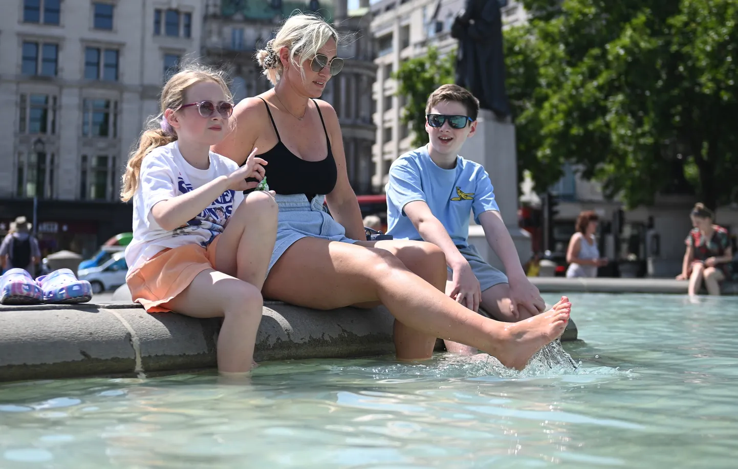Suurbritannias on kuumalaine. Pildil ema ja lapsed jahutamas end Londonis Trafalgari väljaku purskkaevus. Foto on tehtud 18. juulil 2022