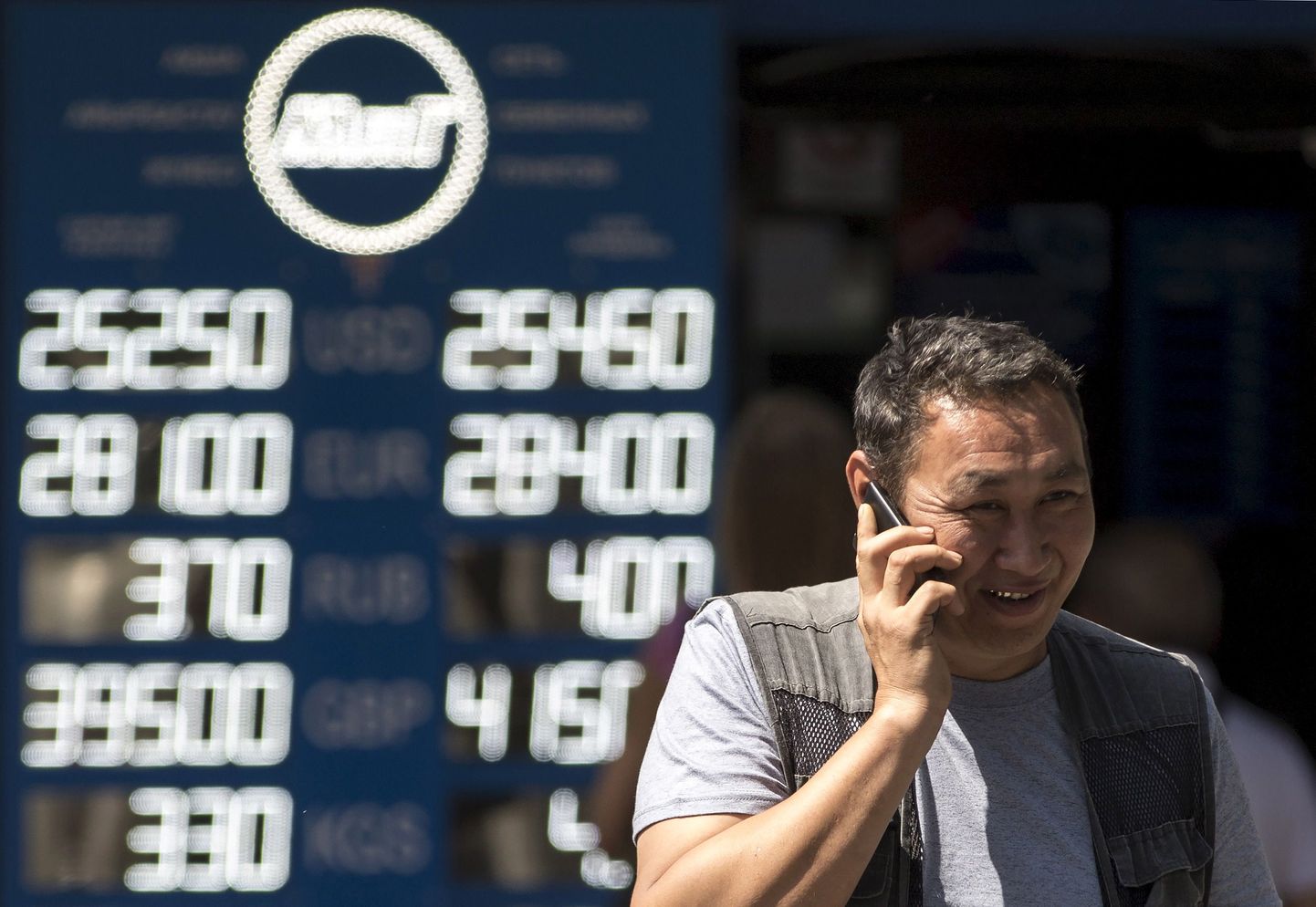 Alma-Atõ elanik valuutavahetuse kursse näitava tabloo ees. Kasahstan devalveeris neljapäeval tenge, kaupmehed reageerisid sellele koheselt kaupade hindade tõstmisega.