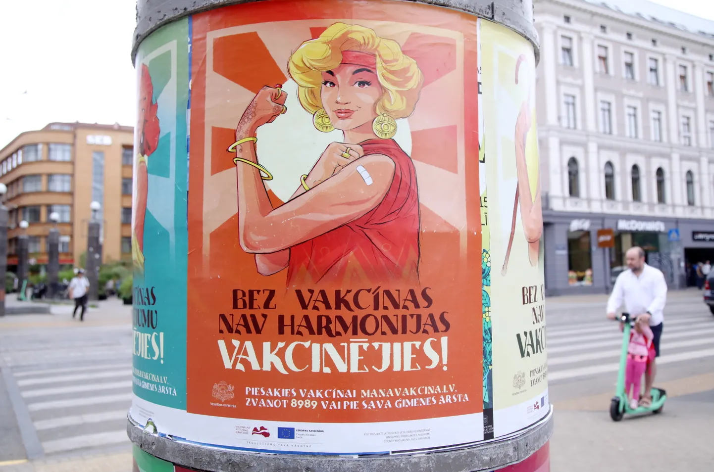 Vakcinācijas pret Covid-19 vides plakāti uz reklāmstaba.