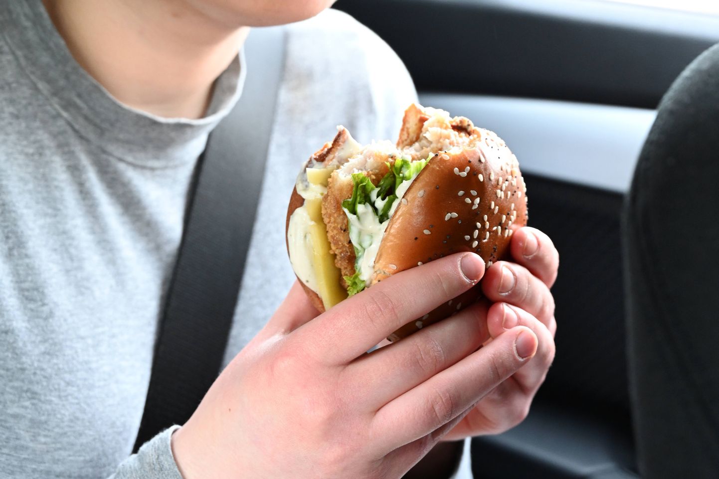 Noor naine autos burgerit söömas.