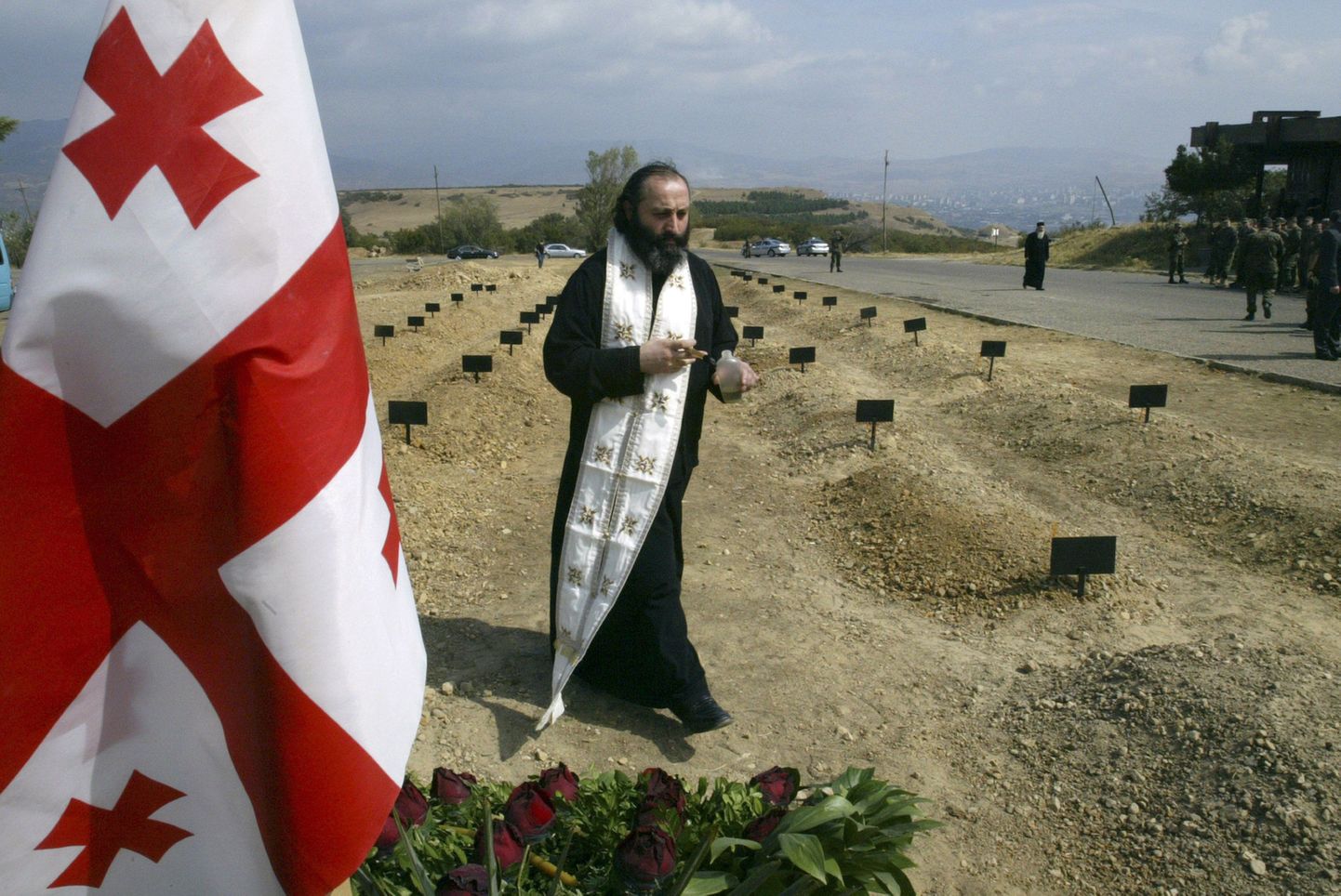 Gruusia preester sõjalises konfliktis hukkunud sõdurite matmispaika õnnistamas.