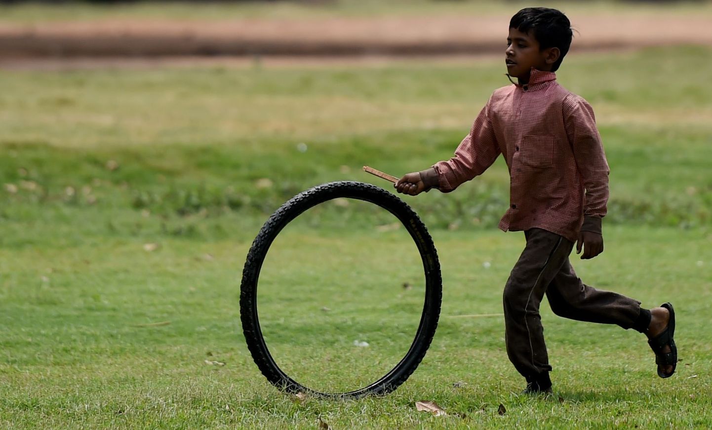 Indiešu zēns spēlējas ar riepu. Ilustratīvs foto. 