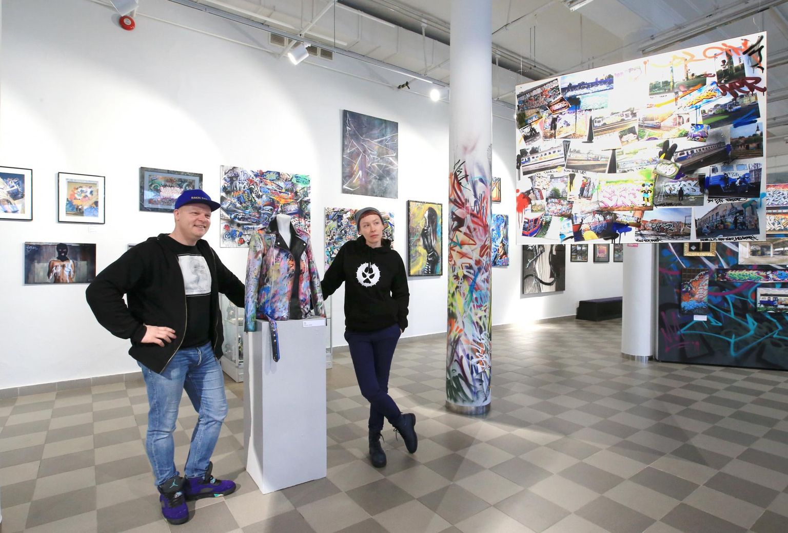 Näituse peakorraldaja Kristjan Bachmani ja kureerida aidanud Salme Kulmari vahel on tallinlasest tänavakunstniku Riku värvipurkidest täiendatud tagi.