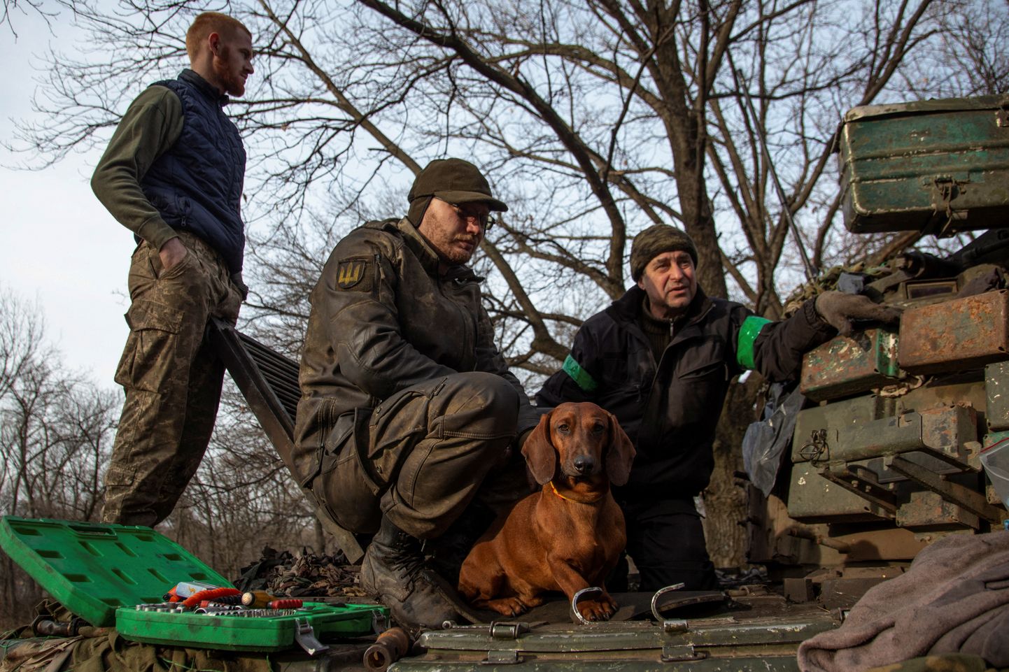 Koer istumas Ukraina sõduritega, kes parandavad tanki Bahmuti rindejoone lähistel,