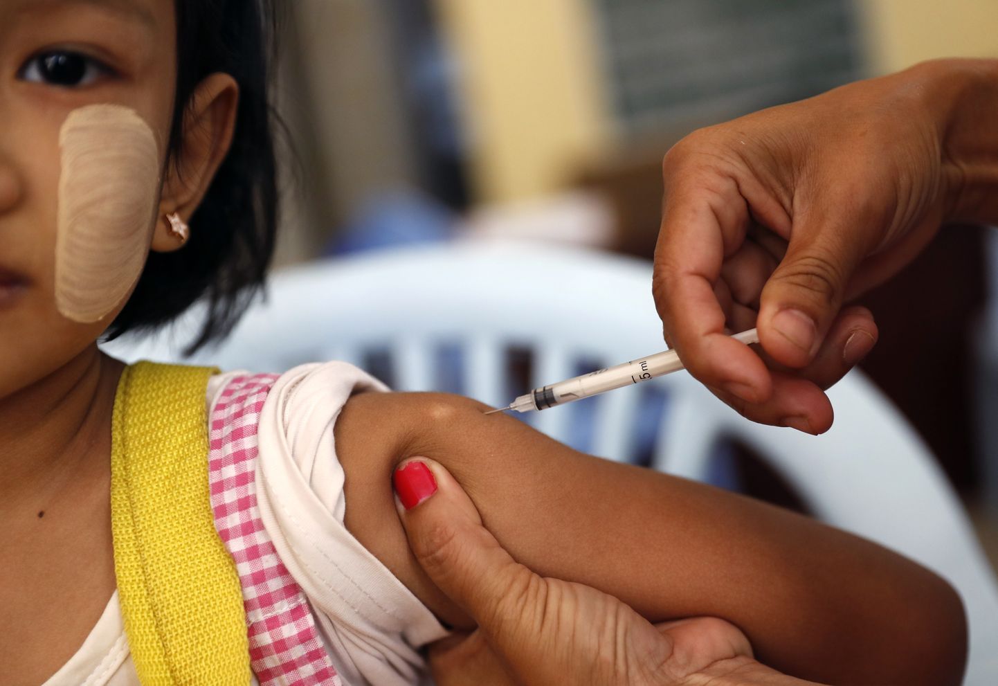 Myanmari tervishoiutöötaja vaktsineerimas tüdrukut leetrite ja punetiste vastu.