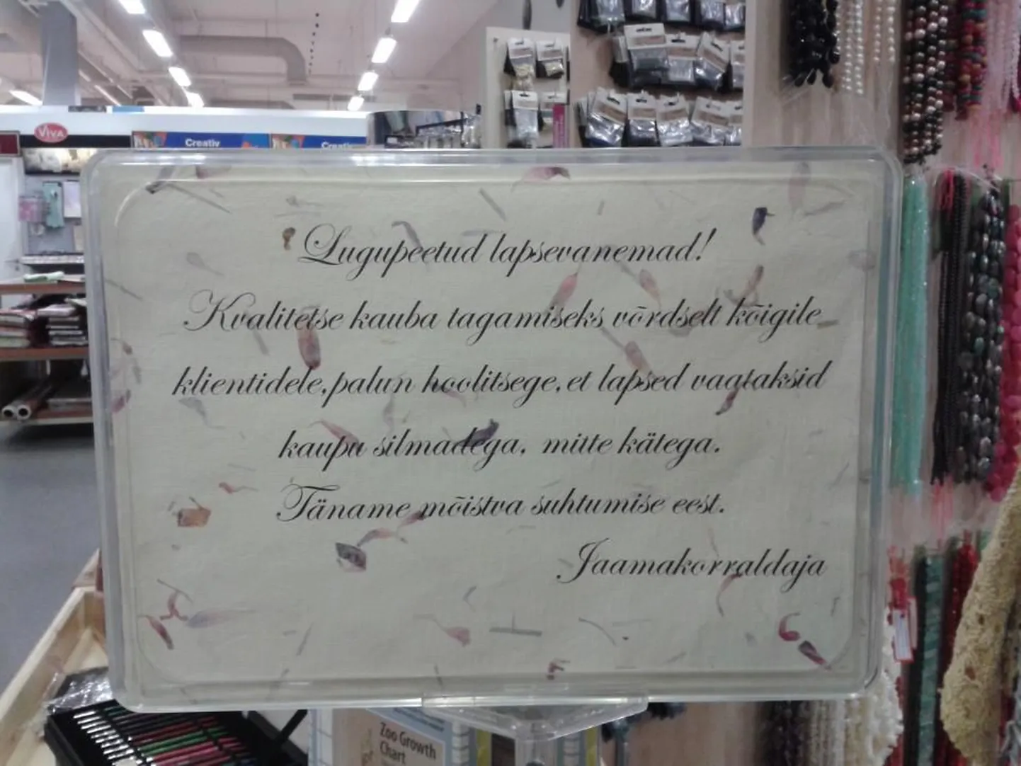 Käsitööjaama uksel olev silt manitseb lapsevanemaid.