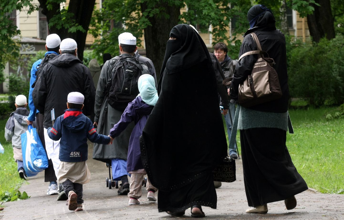 Cilvēki tērpušies tradicionālajā musulmaņu apģērbā pastaigājas Kronvalda parkā.