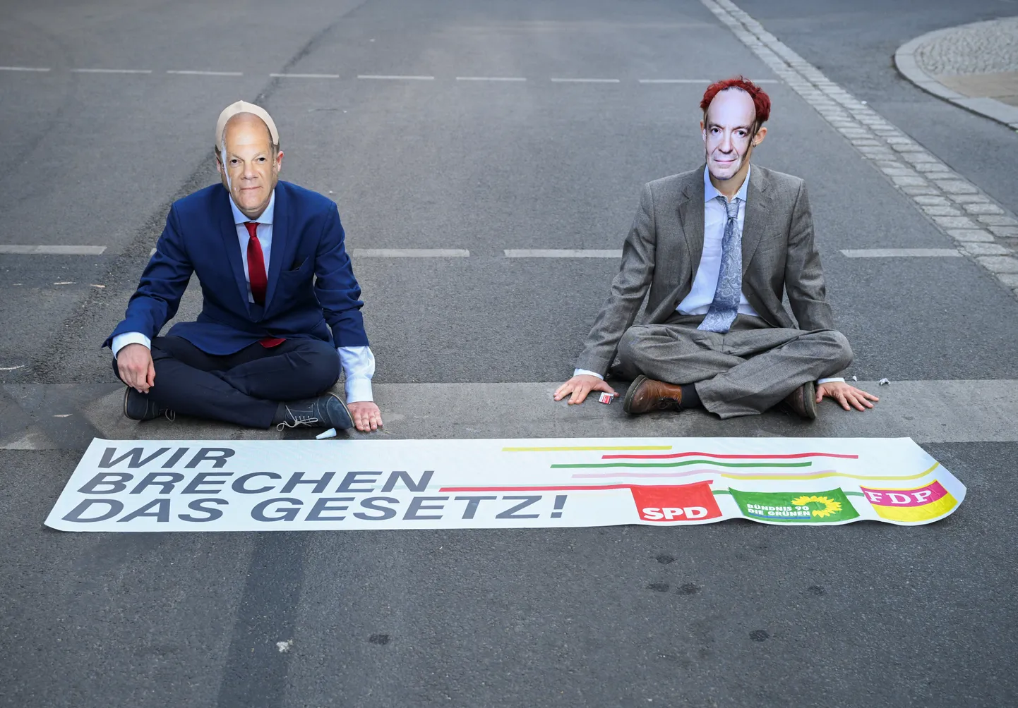 Kliimaaktivistide valitsusvastane protest. 14. juulil 2023 Berliini parlamendihoone lähedal meelt avaldanud noored kandsid kantsler Olaf Scholzi (vasakul) ja transpordiminister Volker Wissingi (paremal) maske. Loosungil on tekst «Me rikume seadust!».